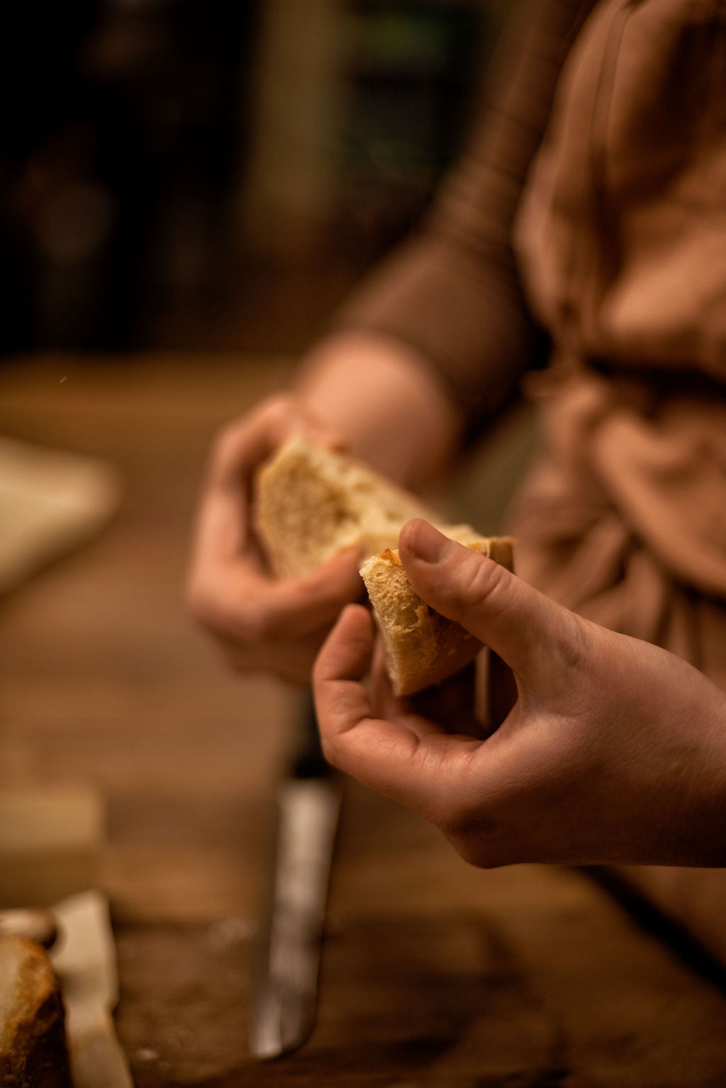 Hands breaking open a freshly baked baguette revealing its airy crumb and open texture during the tasting moment of a bread baking class at Maison Fleuret Paris