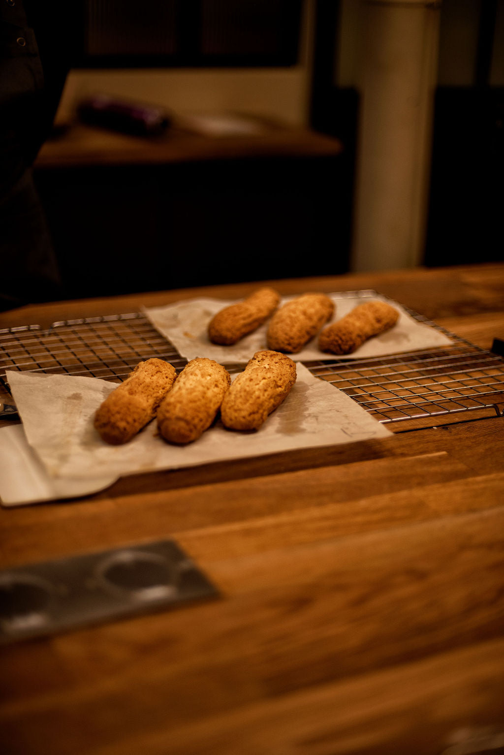 Row of finished eclairs with chocolate glaze on a wooden table in a Paris pastry class