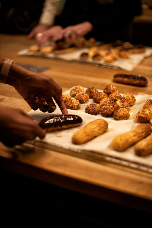 Golden choux buns freshly baked on a dark surface during an eclair and choux pastry class at Maison Fleuret Paris