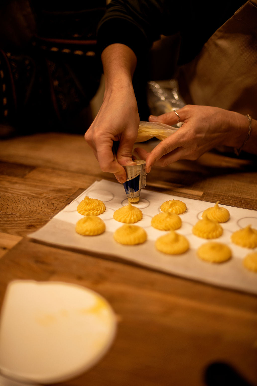 Hands shaping choux pastry under the guidance of a professional pastry chef in Le Marais studio
