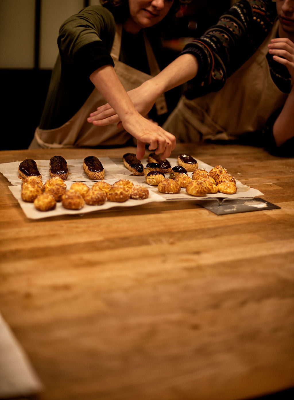 Participants wearing aprons working together on choux pastry in a small group baking experience