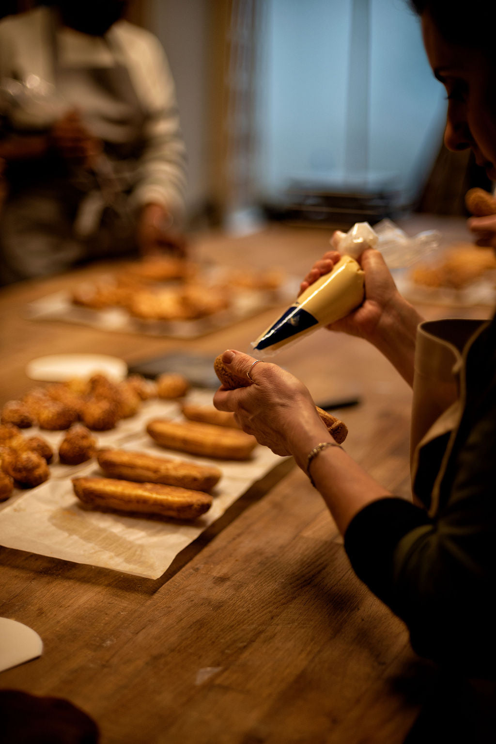 Participant piping choux pastry dough onto a baking sheet during a hands-on workshop at Maison Fleuret