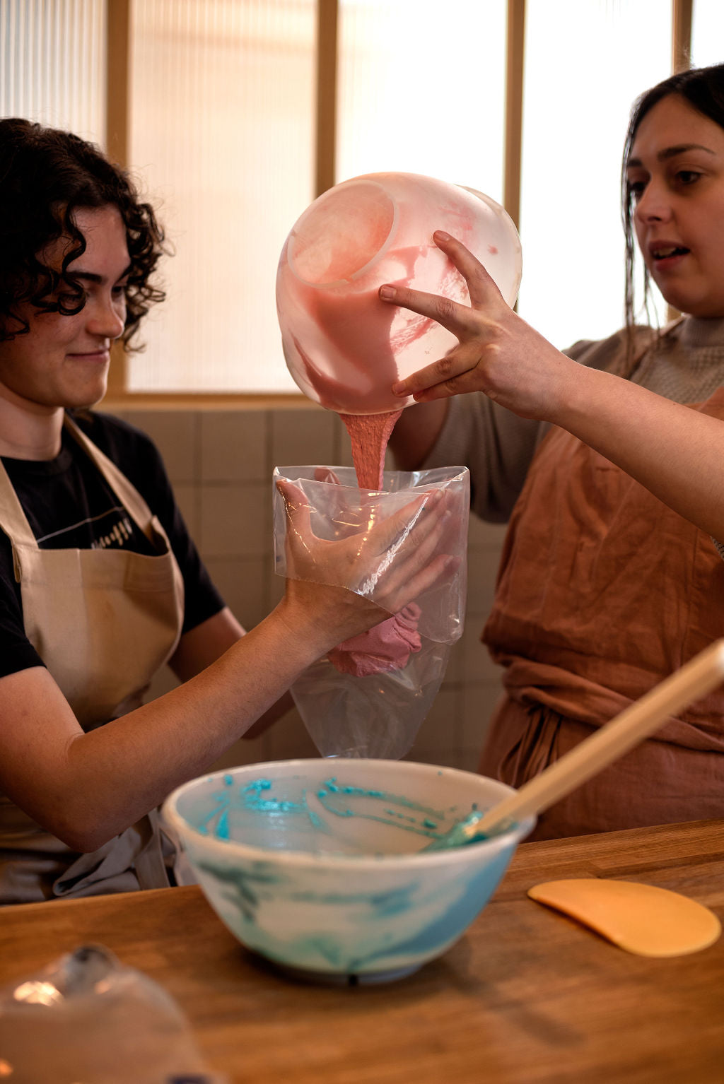 Two participants in aprons mixing macaron batter together during a fun baking experience in Le Marais