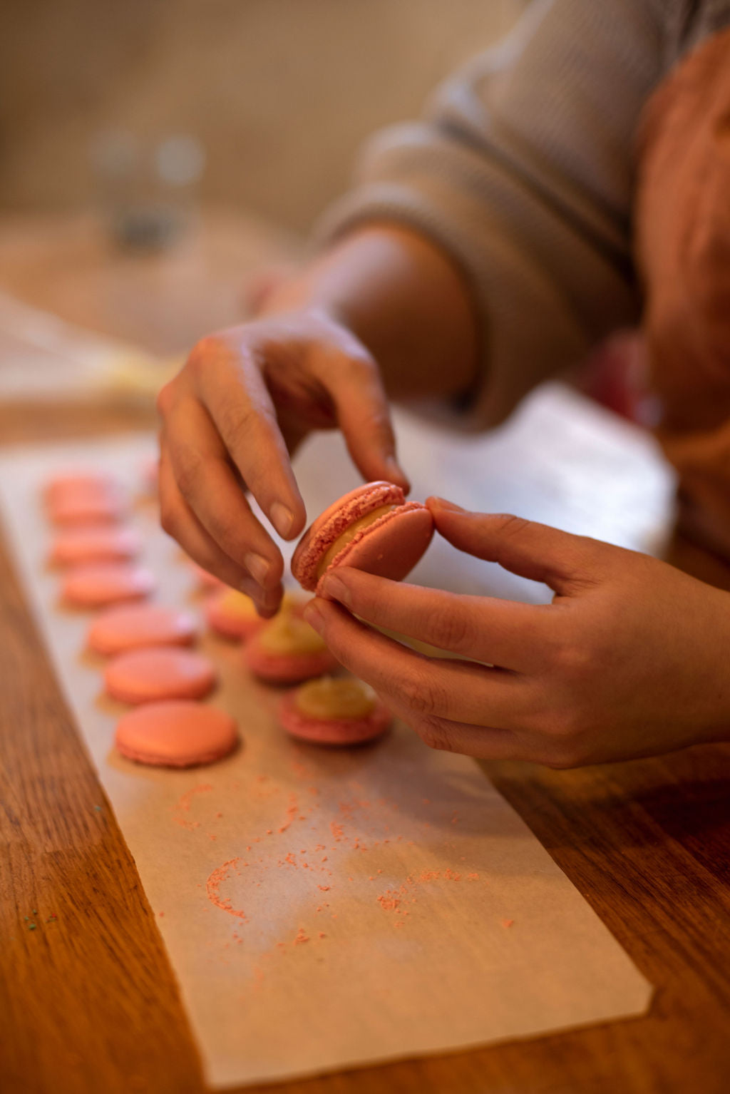 Participant filling and assembling coral macarons with ganache in a hands-on Paris pastry workshop
