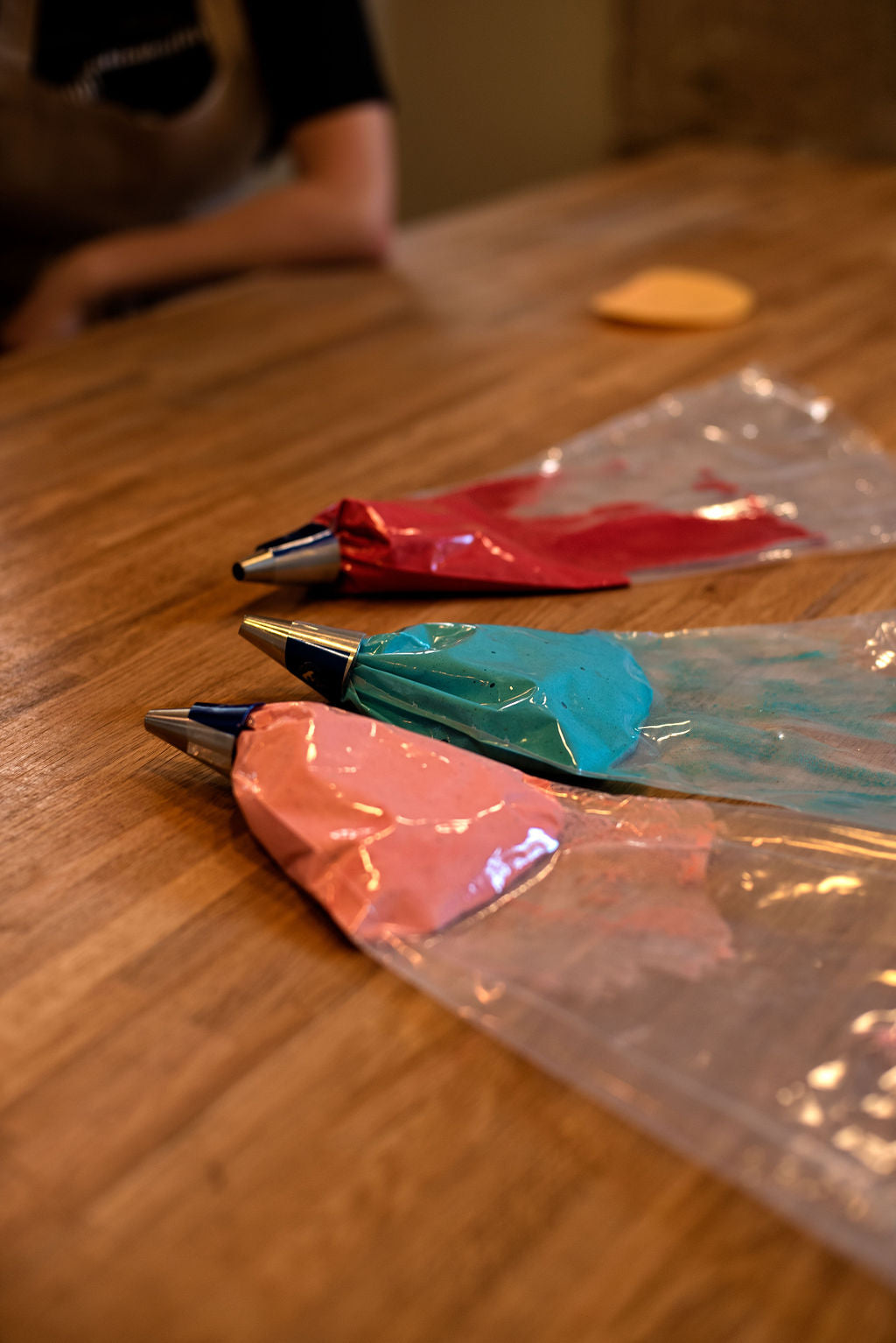 Colorful piping bags filled with red, orange, and blue macaron batter ready for piping in Paris baking class