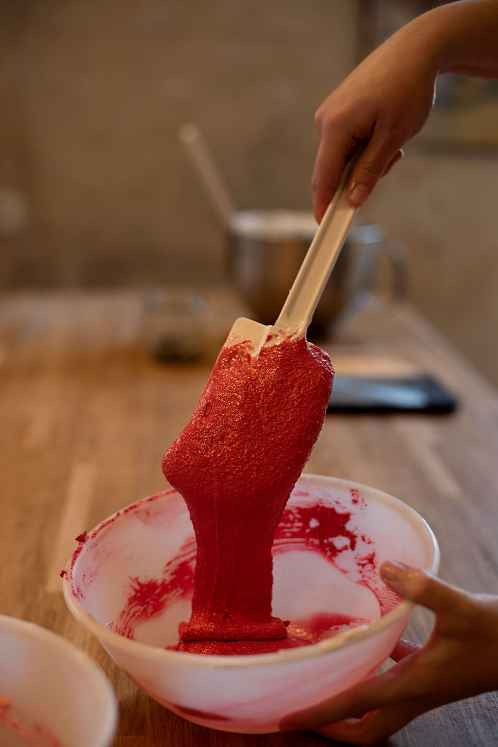 Mixing vibrant red berry filling for macarons in a professional pastry kitchen in Paris