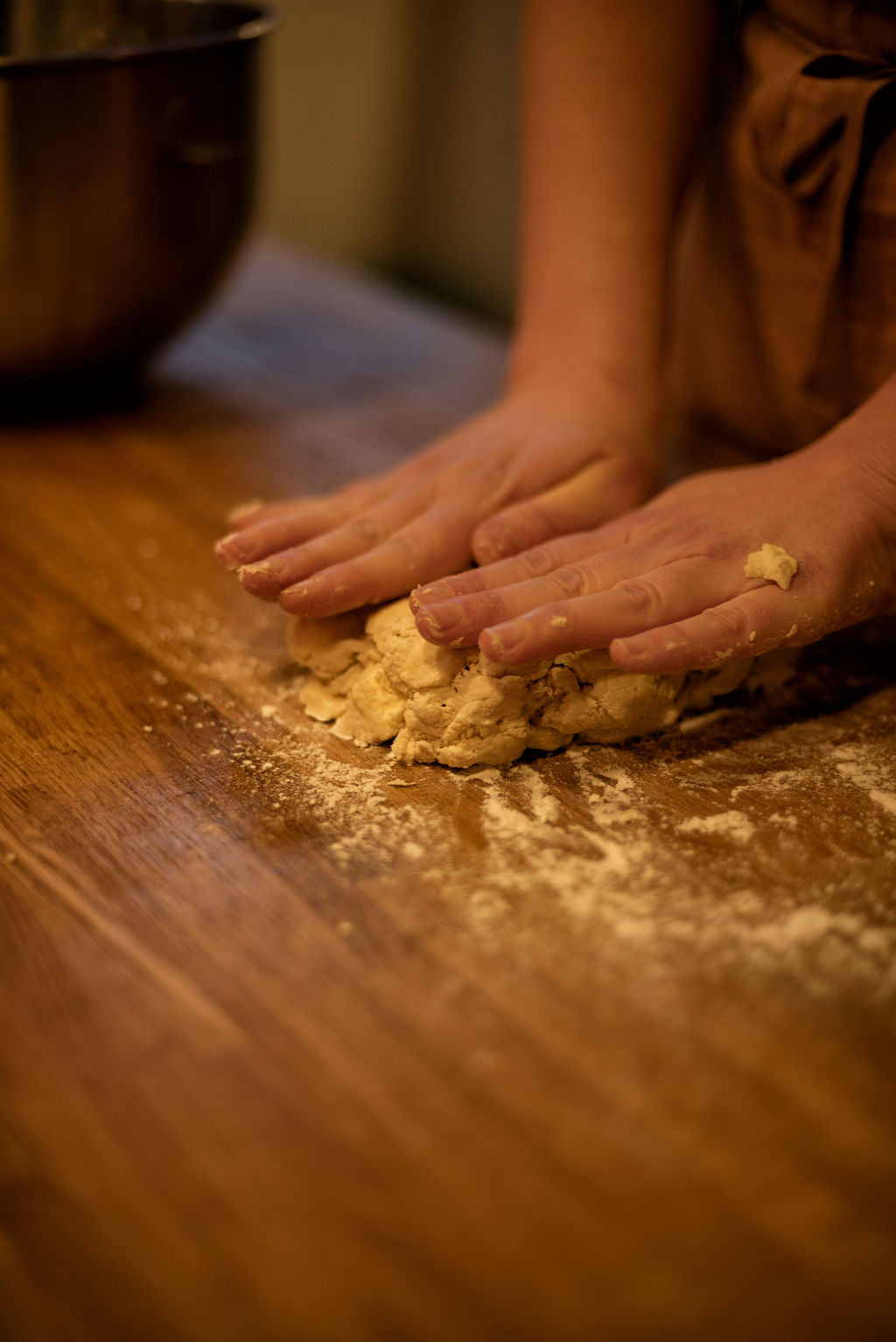 Close-up of hands kneading puff pastry dough on a flour-dusted wooden worktop during a hands-on Napoleon millefeuille baking class at Maison Fleuret Paris