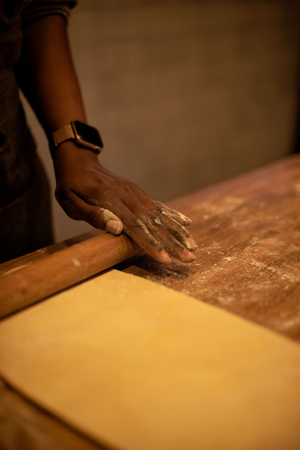 Participant rolling out a thin sheet of puff pastry dough with a wooden rolling pin on a flour-dusted table during a Napoleon millefeuille class at Maison Fleuret Paris